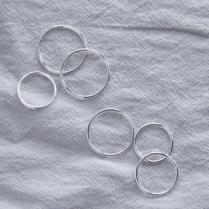 Flat lay of six minimalist S925 sterling silver thin rings on grey linen fabric