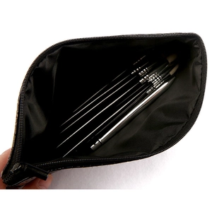 Top view of an open black cosmetic bag with zippers holding professional makeup brushes