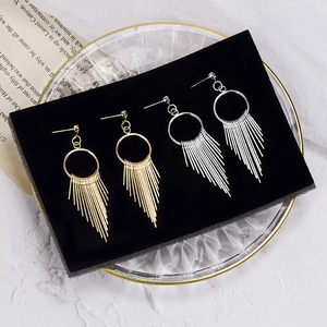 Detail view of gold and silver long metal tassel earrings on black velvet display