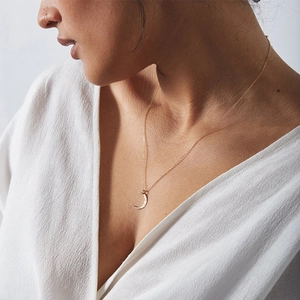 Close-up of a minimalist gold moon pendant necklace on a model for a stylish look