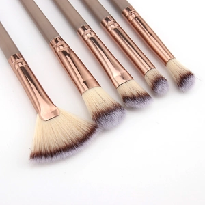 Detail of 5 champagne gold makeup brushes with gradient bristles in a diagonal layout