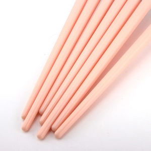Close-up of sleek pink makeup brush handles on a white background with soft shadows
