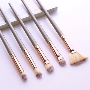 Macro view of 5 champagne gold and gray makeup brushes with gradient soft bristles