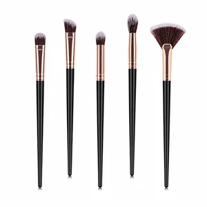 Detail of five makeup brushes with rose gold ferrules and black handles on white background