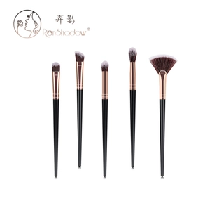 Detail of five makeup brushes with rose gold ferrules and black handles on white background