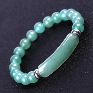 Macro shot of green aventurine stone beads and curved tube bar on a beaded bracelet