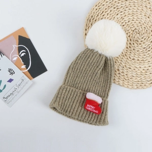 Détail du bonnet de Noël en maille kaki avec pompon en fausse fourrure et broderie rouge