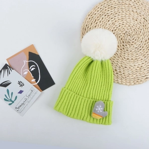 Détail du bonnet de Noël vert avec pompon en fausse fourrure blanche et patch moufle