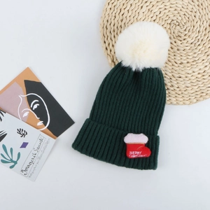 Détail du bonnet de Noël vert foncé avec pompon blanc et broderie festive sur fond blanc