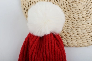 Vue détaillée du bonnet de Noël rouge avec un gros pompon blanc moelleux sur le dessus