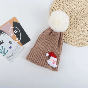 Détail d'un bonnet de Noël en tricot kaki doux avec pompon blanc et applique Père Noël