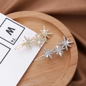 Close-up of gold and silver star-shaped hair clips with sparkling crystals on wood