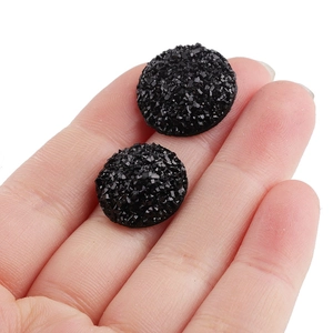 Sparkling black round resin druzy studs shown on fingertips for size scale on white background