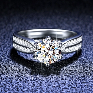 Close-up of a six-prong Moissanite silver ring with side stones on dark blue background