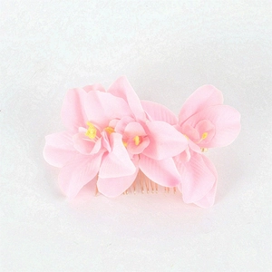 Close-up of three pink fabric orchid flowers on a gold 20-tooth metal hair comb