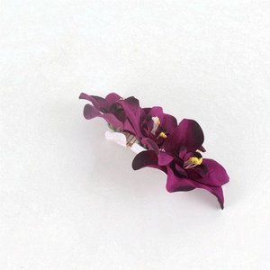 Detailed view of the three purple orchid artificial flowers on the bridal hair comb