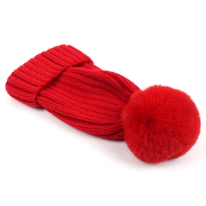 Detail view of the red knitted beanie texture and large matching pom-pom on the top