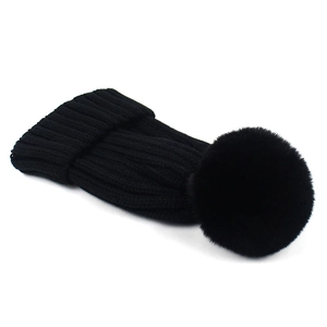 Close-up of black ribbed knit beanie featuring a large fluffy faux fur pom-pom detail