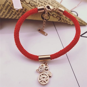 Close-up of red braided rope bracelet with golden mouse charm and coin detail