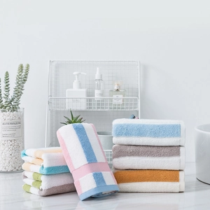 Thickened absorbent cotton towels with colorful stripes in a minimalist bathroom setting