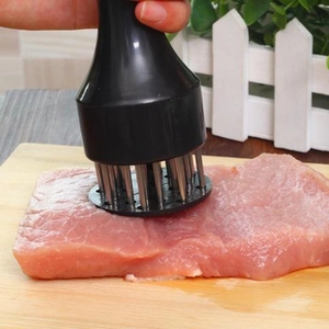 Macro detail of manual meat tenderizer with stainless steel needles on raw meat