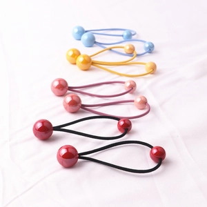 Elastici per capelli colorati con perle sferiche su sfondo di tessuto bianco