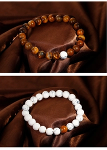 Detailed close-up of tiger eye and marble stone beaded bracelets on silk fabric