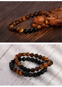 Detailed close-up of tiger eye and matte black beaded elastic bracelet on wood