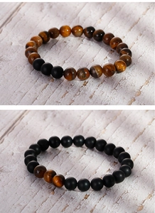 Macro detail of elastic beaded bracelets with tiger eye and matte black agate stones