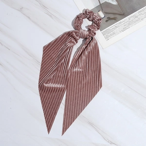 Pink velvet pleated bow scrunchie with long ribbons on white marble background