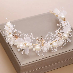 Elegant bridal headband with handmade pearls and golden leaves on a display stand