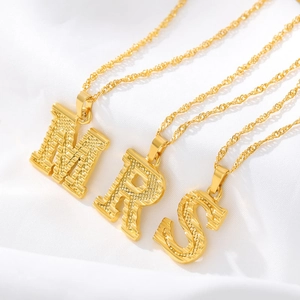 Detailed macro shot of 18k gold plated butterfly letter pendants on soft white fabric