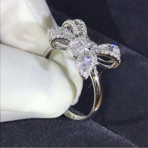Luxurious silver bow ring with baguette diamonds displayed on a black velvet background