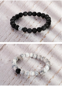 Close-up of black lava rock and white turquoise beaded bracelets for couples on textured stone