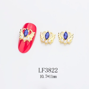 Détail du bijou d'ongle couronne dorée avec pierre bleue et perles, modèle LF3822