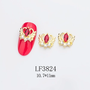 Détail macro de charmes d'ongles ailes et couronne avec pierre rouge pour nail art