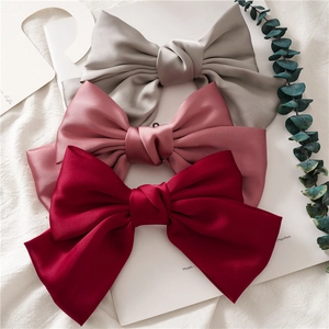 Three satin bow hair clips in grey, pink, and burgundy silk fabric on a white card