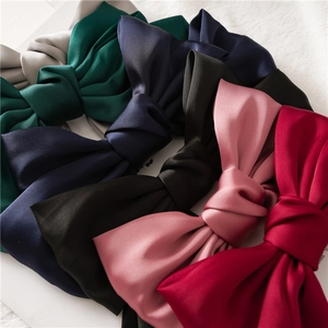 Detail of six satin bow hair clips in red, pink, black, blue, green and grey