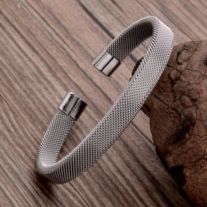 Gros plan du bracelet jonc en maille argentée sur un fond de bois et d'écorce naturel