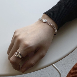 Detail of 925 sterling silver chain bracelet with square charms and engraved star ring