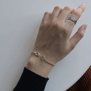 Detail of 925 sterling silver knotted heart bracelet with OT buckle and floral ring