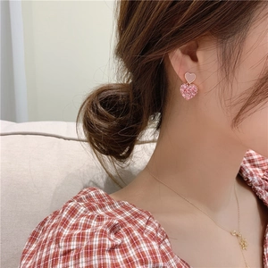Pink heart-shaped drop earrings with pavé crystals and gold-tone finish on model