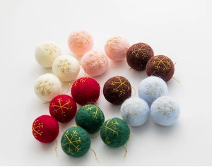 Detailed view of handmade wool felt Christmas balls with gold snowflake embroidery
