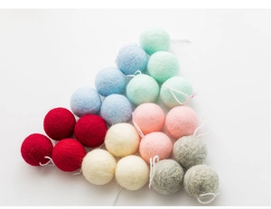 Close-up of colorful handmade wool felt balls in red, cream, and pastel shades for DIY decor
