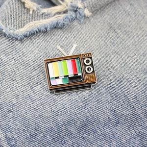 Retro TV enamel pin with colorful signal test pattern on blue denim fabric background