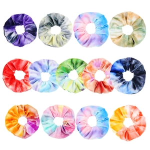 Flat lay of 12 tie-dye velvet hair scrunchies in various gradient colors on white background