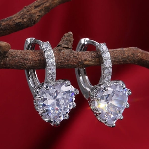 Macro shot of silver heart earrings with sparkling zircons on a rustic wood branch