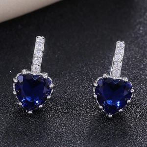 Macro shot of silver heart earrings featuring deep blue crystals and fine zircons