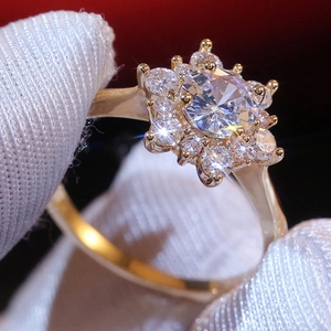 Macro di un anello a fiore dorato con pietre di zircone tenuto da guanti bianchi