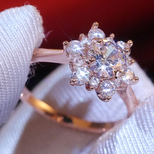Dettaglio macro dell'anello a fiore in oro rosa con zirconi su una mano guantata